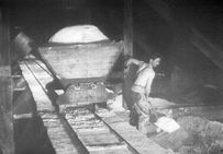 Chargement du sel dans un wagonnet pour le transport du sel au magasin dans une saline franc-comtoise, années 1920-1930.